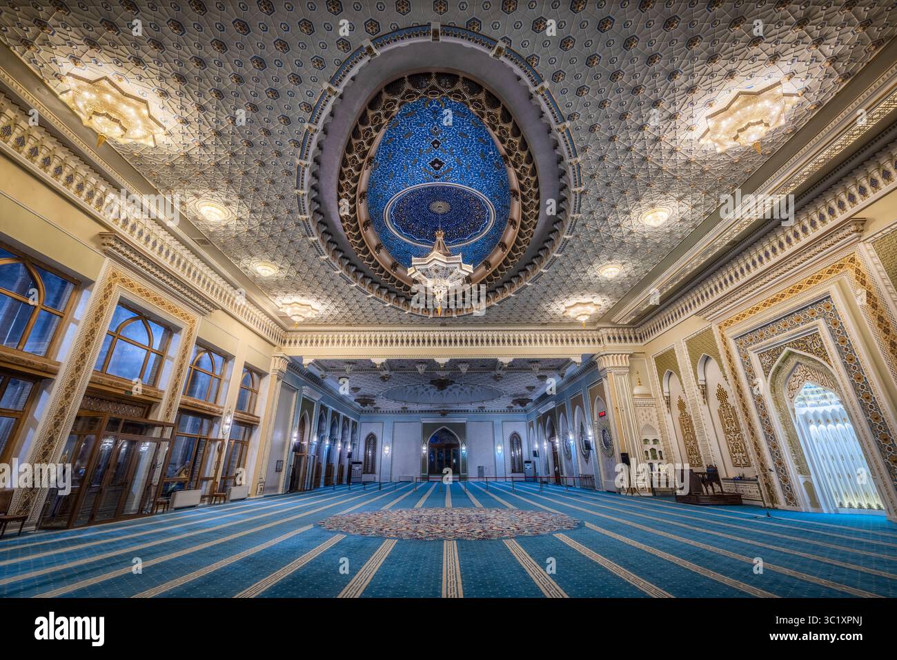 Tachkent, Ouzbékistan - 05 avril 2024 : vue de l'intérieur de la mosquée, avec des motifs bleus complexes sur le sol contrastant avec le plafond orné et le lustre. Banque D'Images