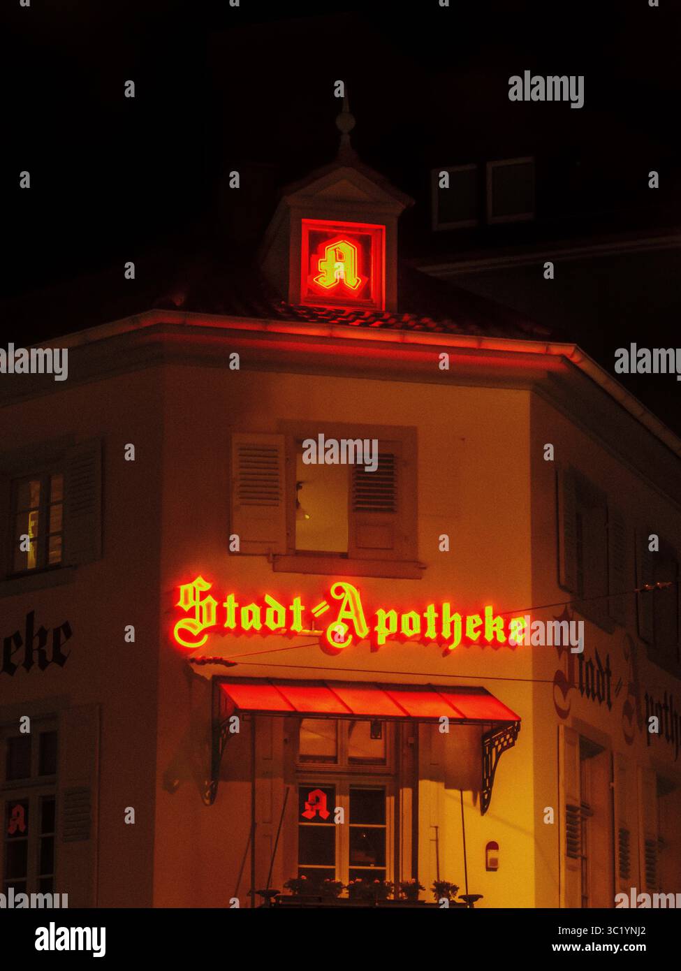 Enseigne de pharmacie urbaine allemande illuminée la nuit sur la façade du bâtiment, Karlsruhe, Europaplatz Banque D'Images