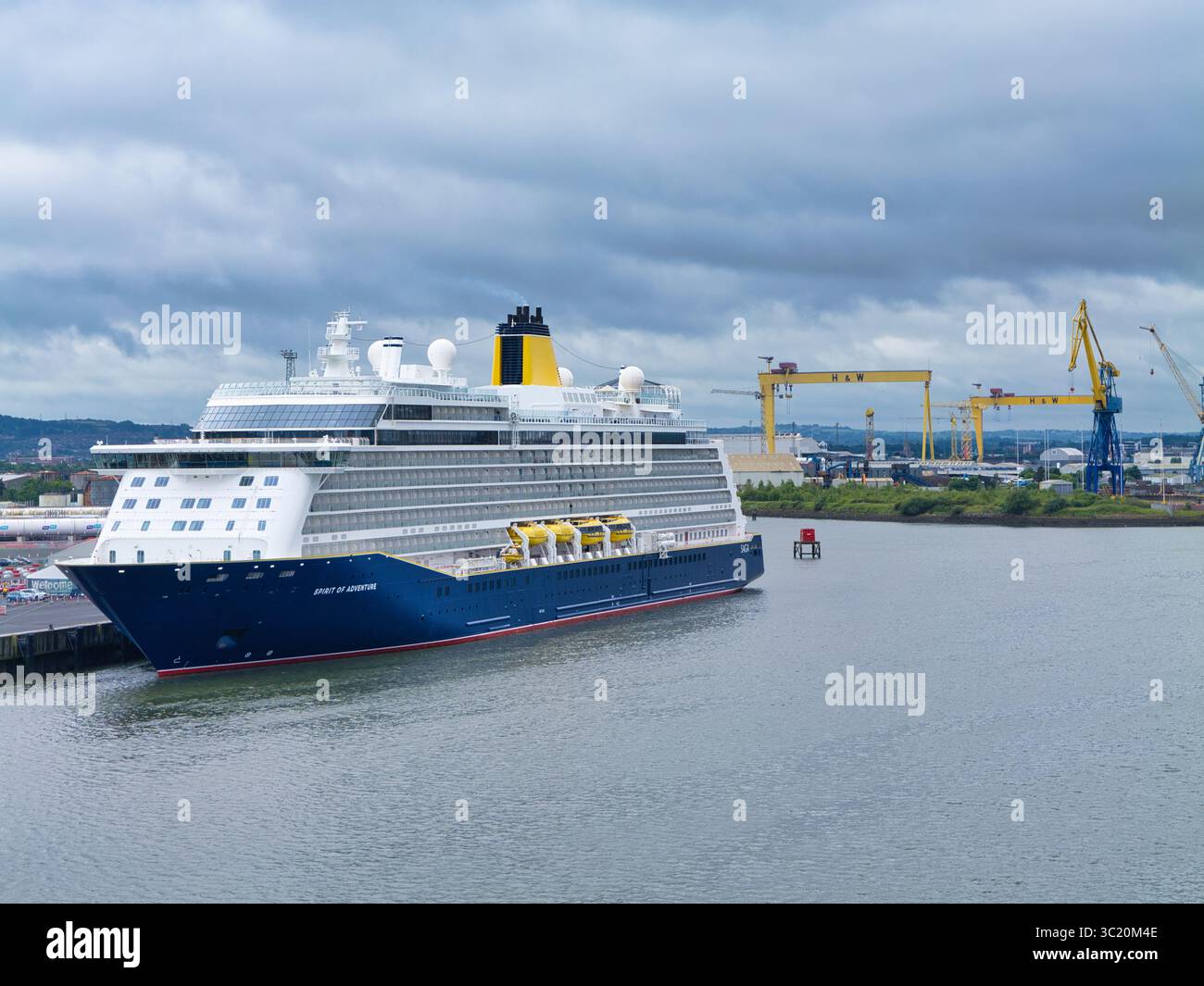 Belfast, Royaume-Uni - 15 juin 2025 : bateau de croisière Spirit of Adventure amarré avec les légendaires grues Harland et Wolff à Belfast en toile de fond. Banque D'Images