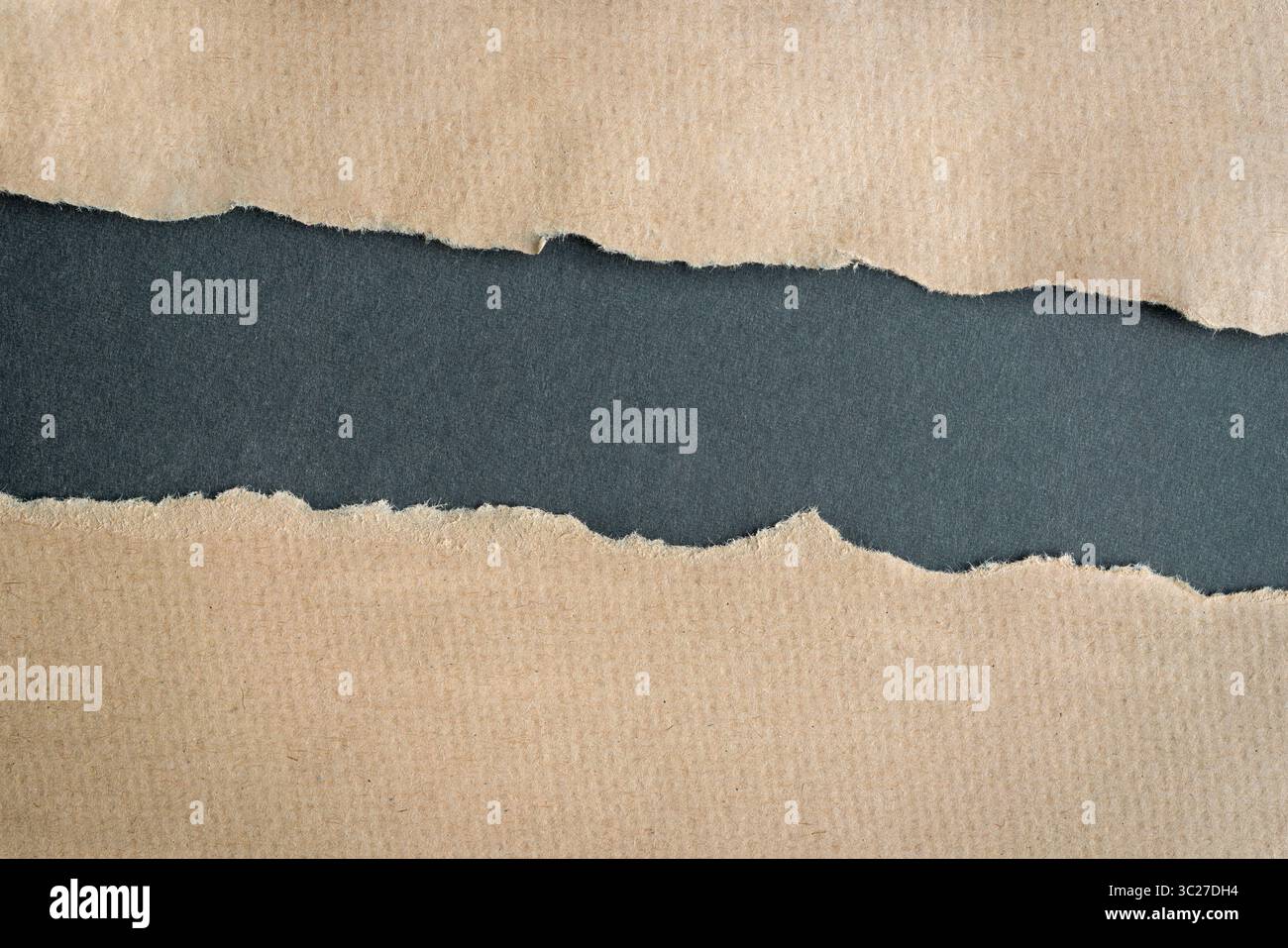 Carton brun papier déchiré bords déchirés laissant un trou horizontal au centre, sur fond gris foncé. Copier l'espace. Banque D'Images
