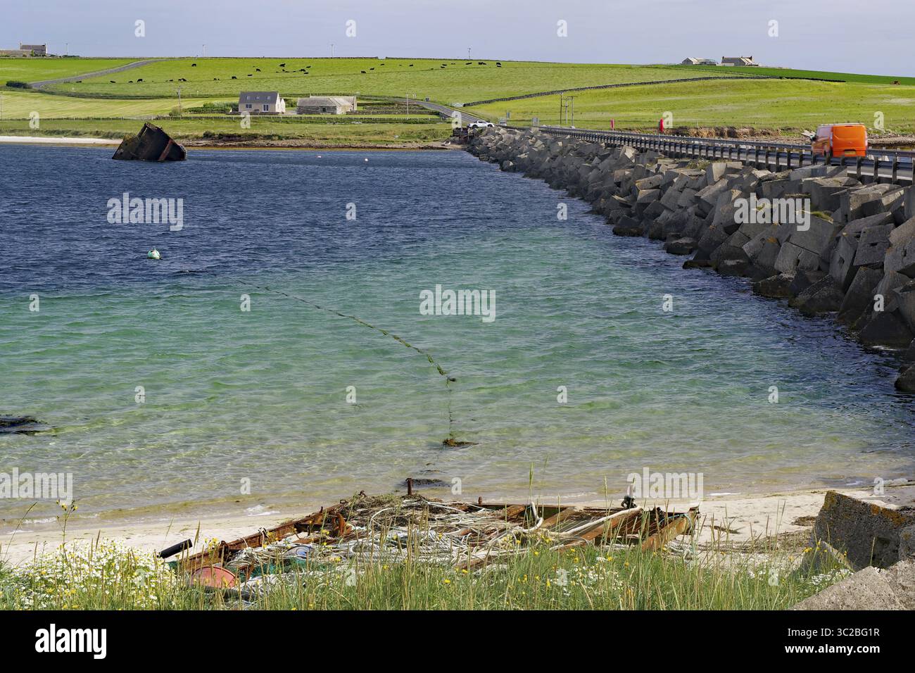 Ruine d'un bateau sur la plage avec un brise-lames et fond côtier vert, Churchill Bariers, Lambholm, Scapa Flow, Orcades, Écosse, unie Banque D'Images