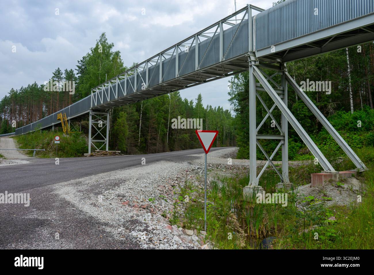 Structure de bande transporteuse surélevée dans une zone minière, s'étendant à travers un paysage boisé Banque D'Images
