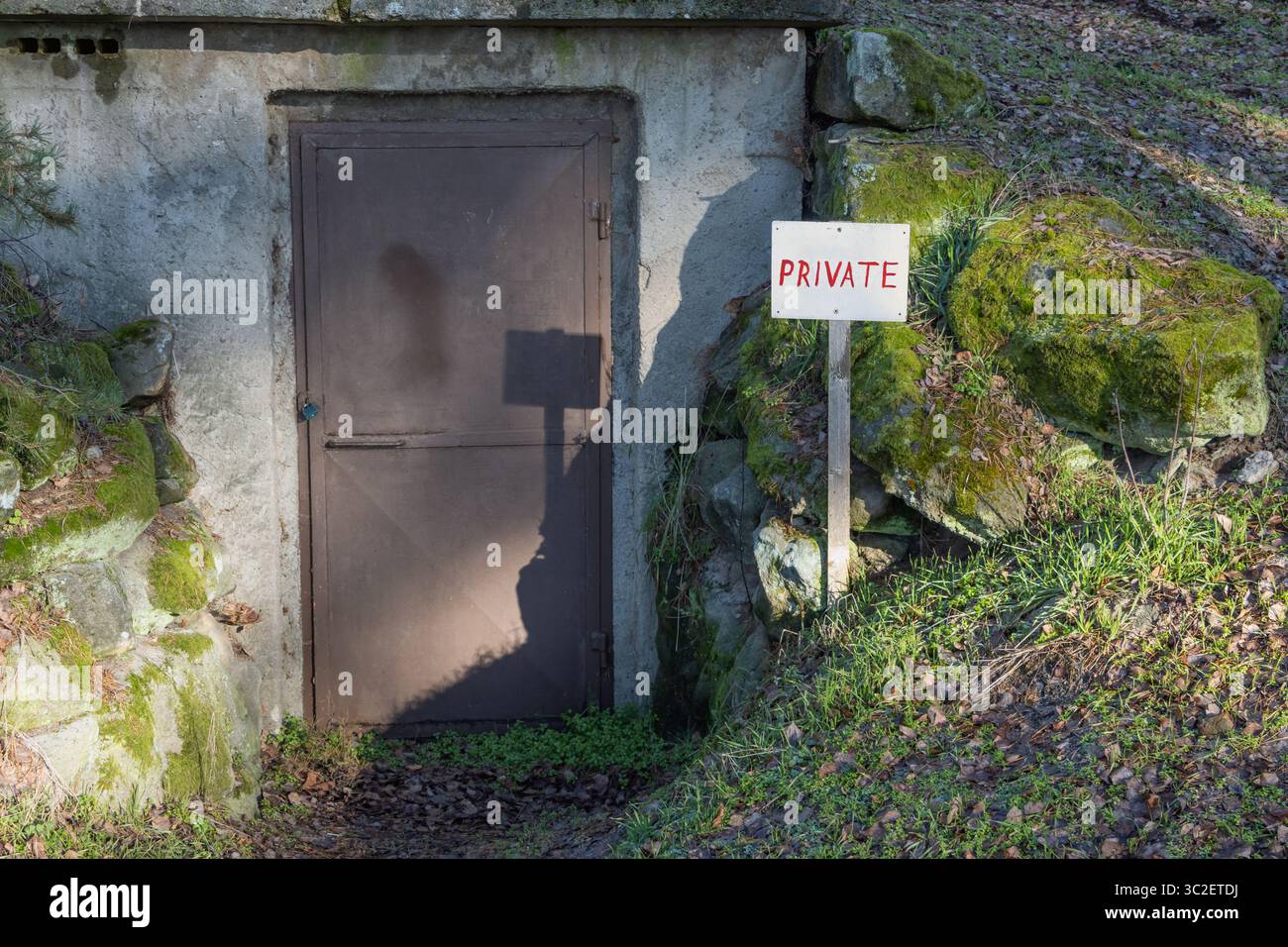 Une porte métallique verrouillée dans une colline rocheuse, avec un signe privé proéminent. Banque D'Images