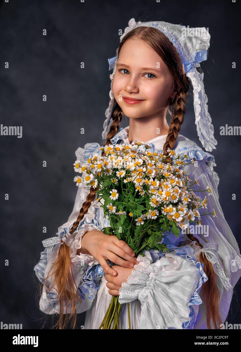 Fille souriante dans la robe vintage tenant un bouquet de marguerites sur fond sombre Banque D'Images