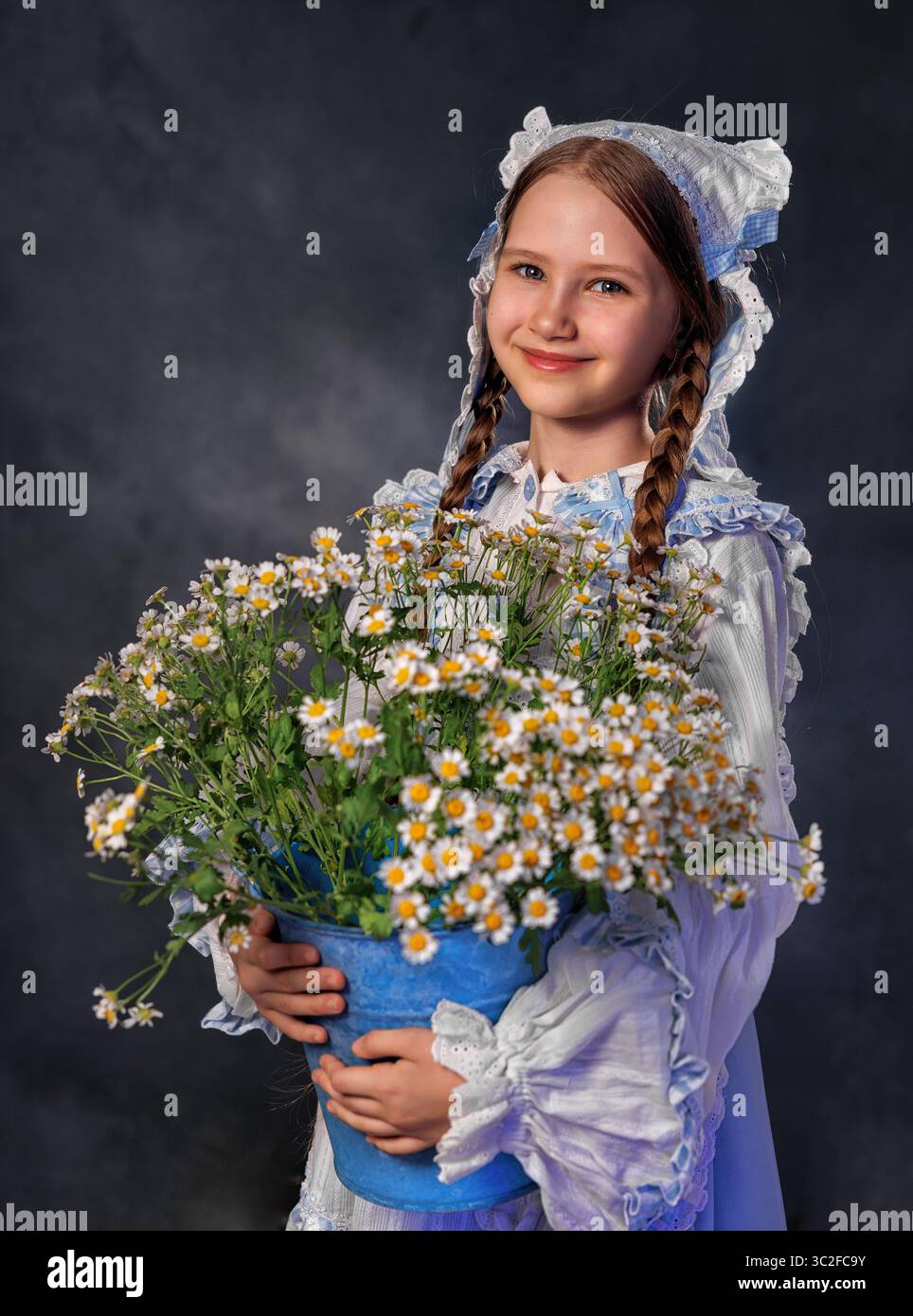 Fille souriante dans la robe vintage tenant un bouquet de marguerites sur fond sombre Banque D'Images