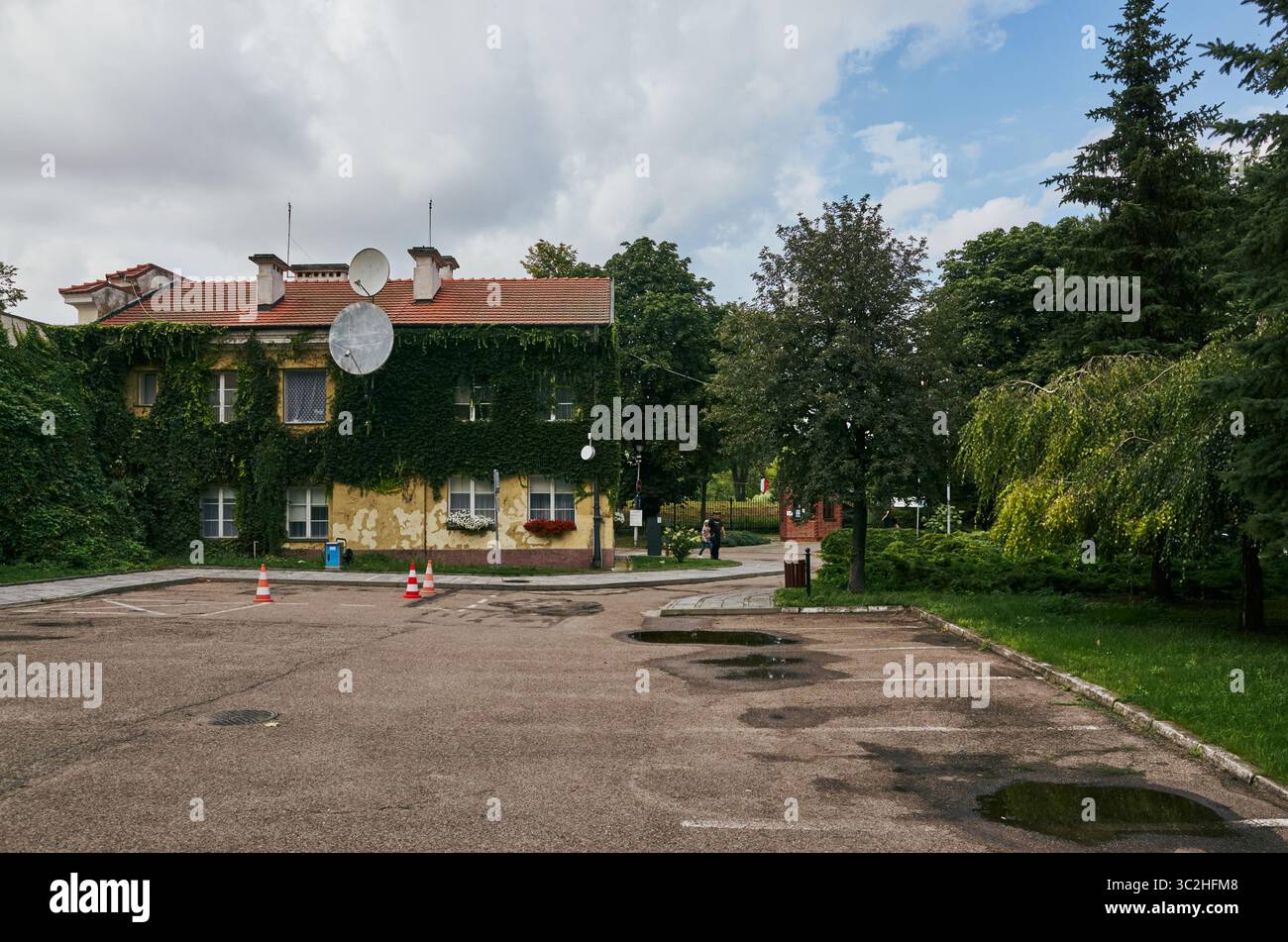 Maison avec une antenne parabolique sur le toit. La maison est entourée d'arbres et a beaucoup de lierre poussant dessus. Pultusk, Pologne 20.07.2025 Banque D'Images