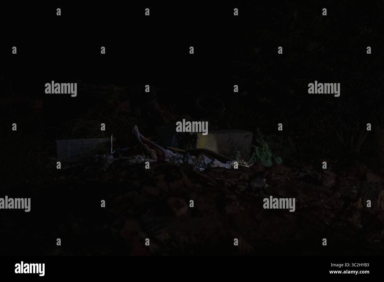 Au milieu des décombres de Ciudad Juarez, les jambes d'une personne émergent dans une zone sombre et violente la nuit. Banque D'Images