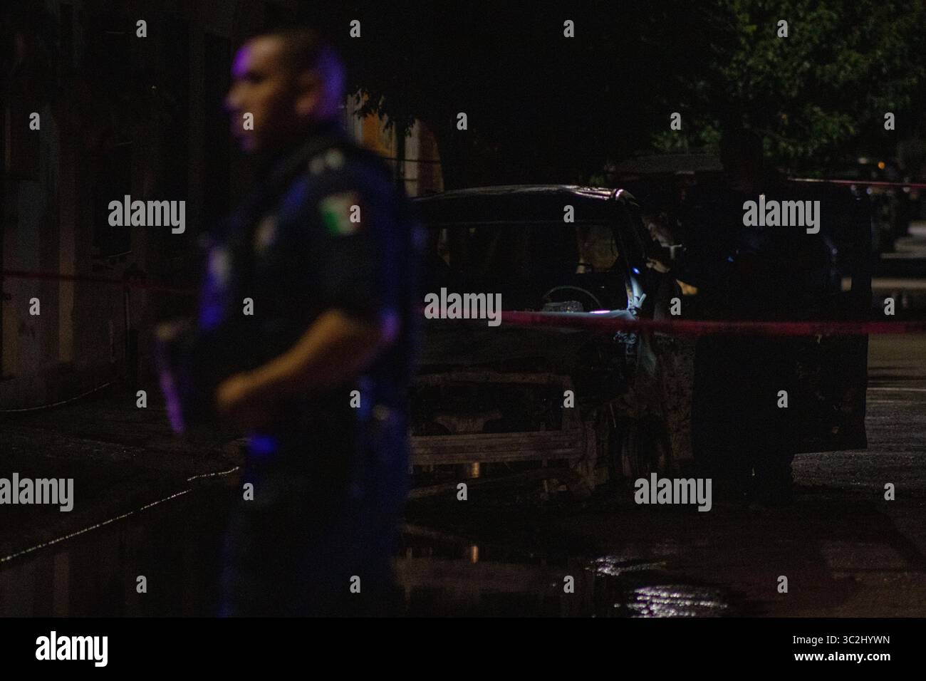Un policier inspecte une voiture brûlée à Ciudad Juarez, un haut lieu de la violence urbaine. Banque D'Images