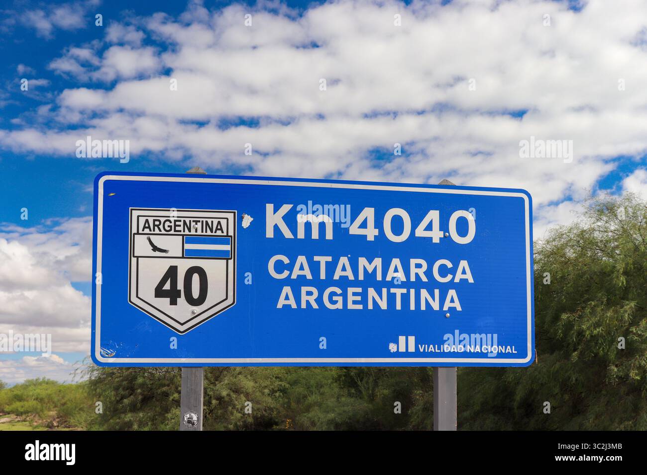Un panneau bleu clair de la route nationale indique km 4040 et Catamarca Argentina sur la route 40, sous un ciel vibrant avec des nuages, en se concentrant sur les informations clés. Banque D'Images