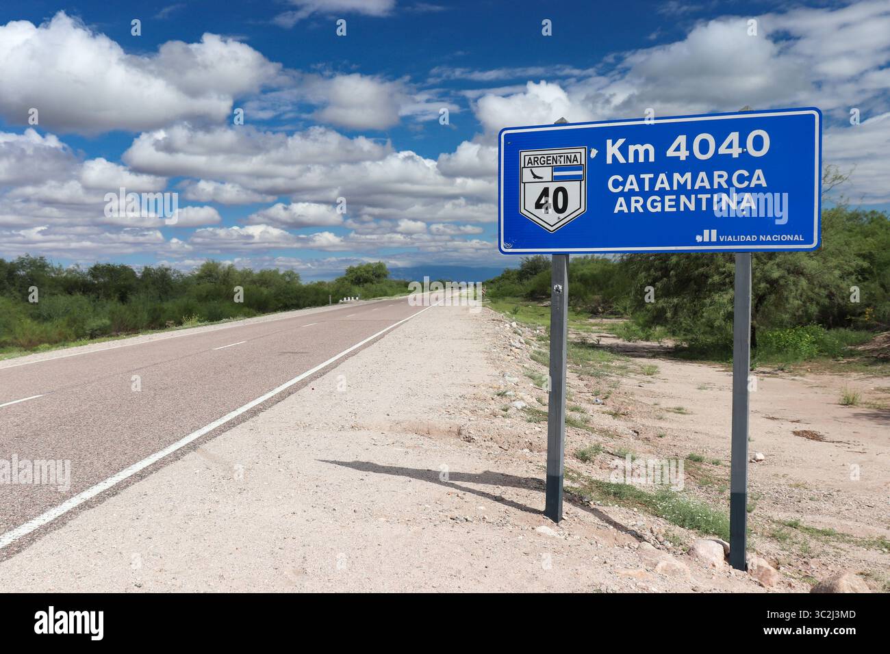 Un panneau routier bleu indique la distance et la direction sur l'emblématique route 40, pointant vers le km 4040 vers Catamarca, Argentine, sous un ciel partiellement nuageux Banque D'Images