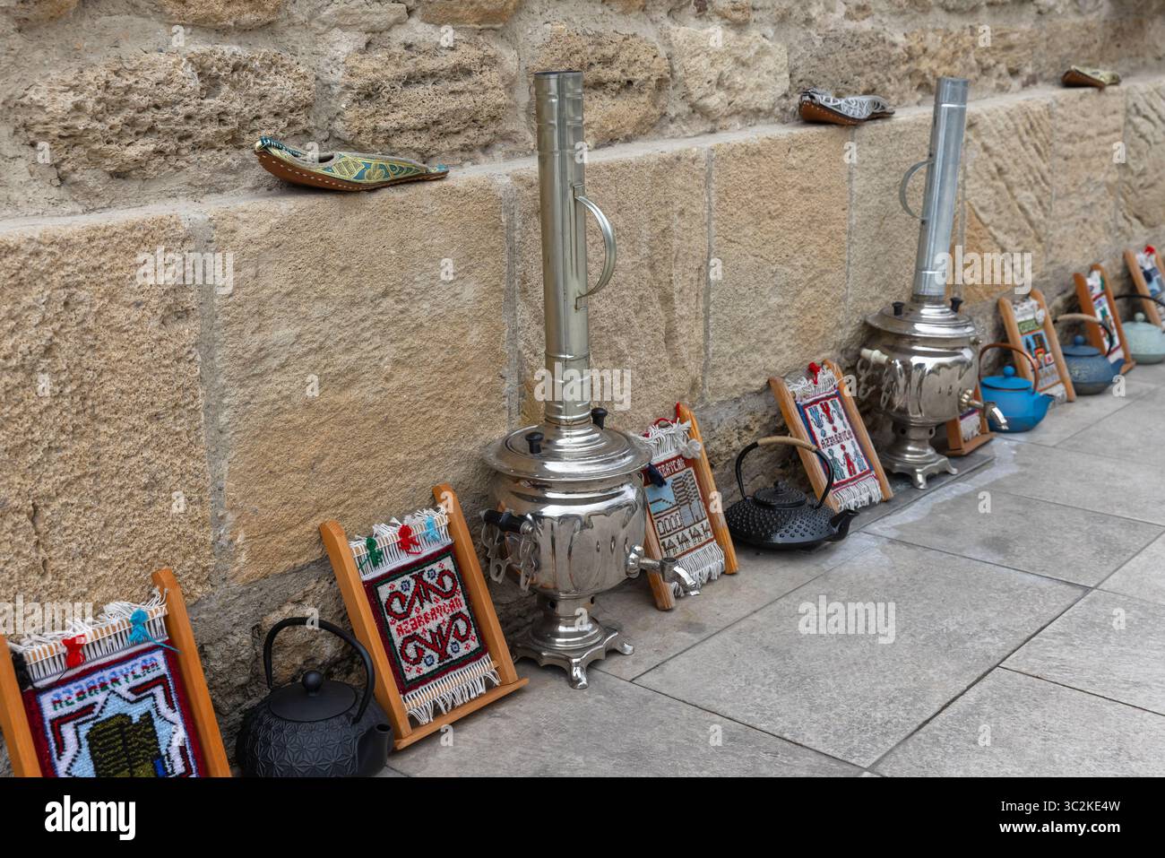 Marché de rue avec des objets traditionnels, y compris un samovar brillant, des textiles tissés artisanaux et des bouilloires rustiques magnifiquement exposées contre un salut Banque D'Images