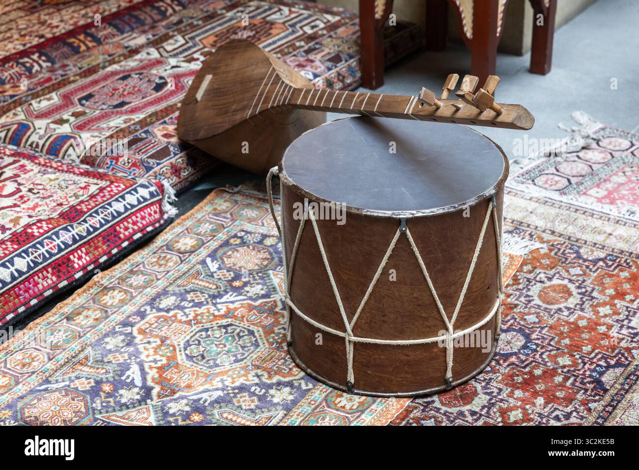 Un tambour en bois traditionnel et instrument à cordes placé sur des tapis colorés à motifs. Le baglama ou saz est une famille d'instruments à cordes pincées et lo Banque D'Images