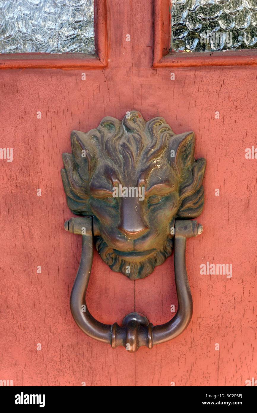 Gros plan d'une porte en métal frappant sur une porte en bois rouge, représentant probablement le Dieu grec Pan ou le Dieu romain Faunus Banque D'Images