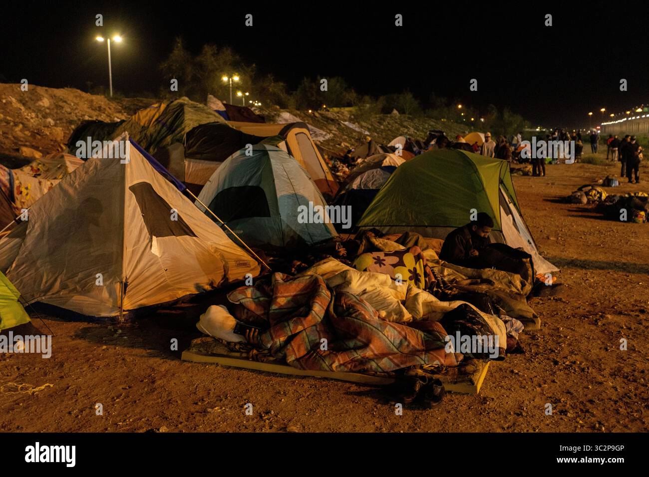 Des tentes de fortune parsèment la zone frontalière poussiéreuse de Ciudad Juarez la nuit, fournissant un refuge temporaire aux migrants déplacés par les tensions frontalières américano-mexicaines et les politiques migratoires. Banque D'Images