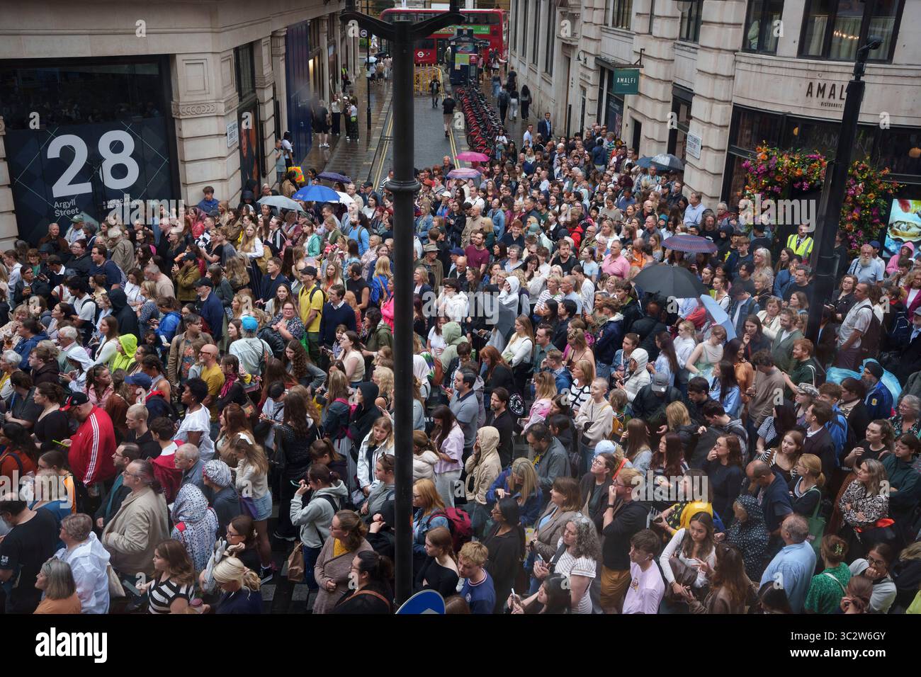 Une vue aérienne des foules qui attendent sous la pluie devant le palladium Theatre sur Argyll Street où l'actrice Rachel Zegler va bientôt émerger sur un balcon pour chanter "Don't Cry for me Argentina" dans le cadre de sa prestation en matinée dans le rôle d'Evita Peron, le 24 juillet 2025, à Londres, en Angleterre. Rachel Zegler sort et chante la chanson emblématique pour le public dans la rue ci-dessous mais fait également partie de la production musicale et est relayée par des caméras au public à l’intérieur. Argyll Street est bloqué à chaque performance pour la circulation uniquement pendant les quelques minutes de la chanson. Banque D'Images