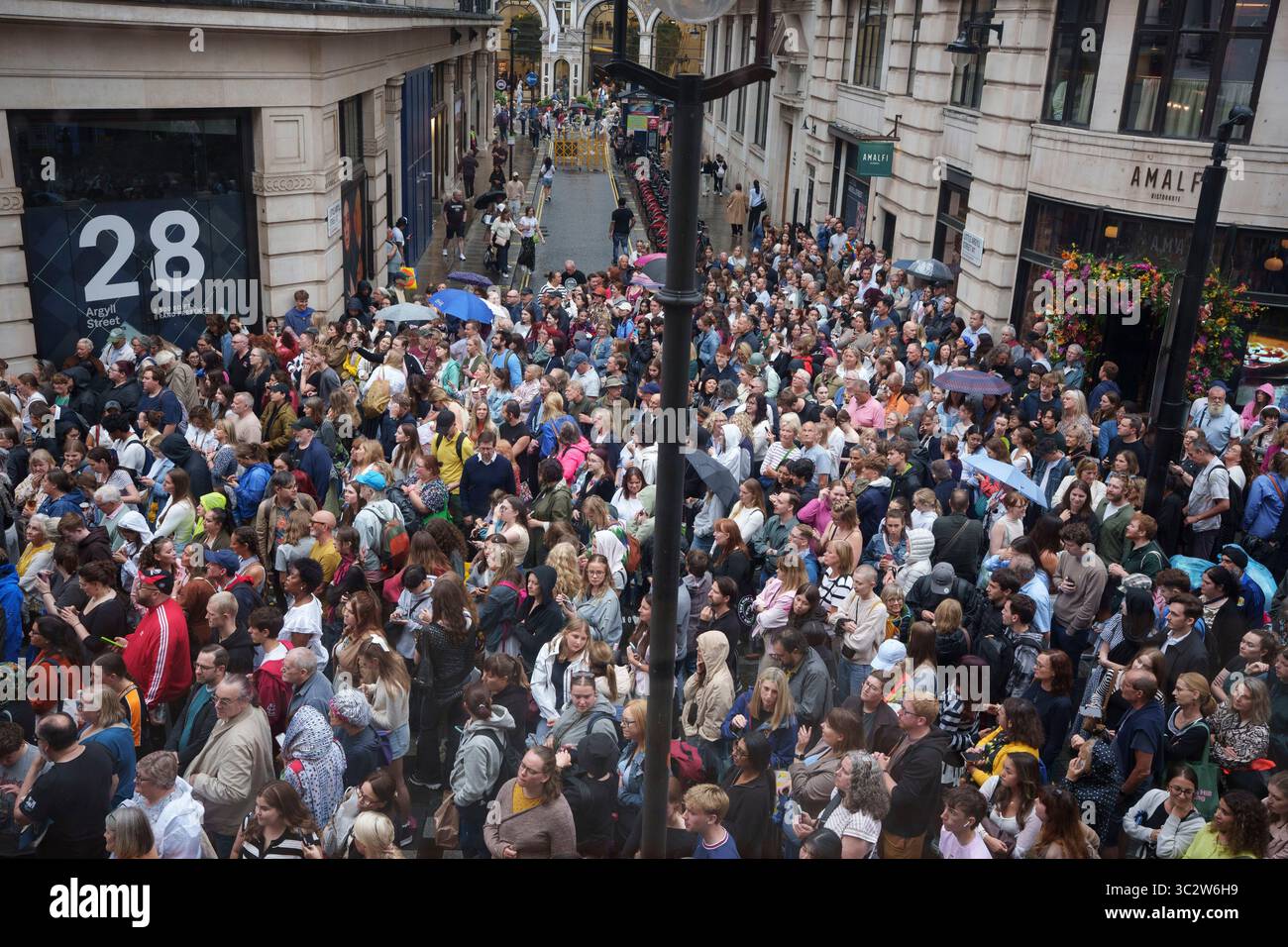 Une vue aérienne des foules qui attendent sous la pluie devant le palladium Theatre sur Argyll Street où l'actrice Rachel Zegler va bientôt émerger sur un balcon pour chanter "Don't Cry for me Argentina" dans le cadre de sa prestation en matinée dans le rôle d'Evita Peron, le 24 juillet 2025, à Londres, en Angleterre. Rachel Zegler sort et chante la chanson emblématique pour le public dans la rue ci-dessous mais fait également partie de la production musicale et est relayée par des caméras au public à l’intérieur. Argyll Street est bloqué à chaque performance pour la circulation uniquement pendant les quelques minutes de la chanson. Banque D'Images
