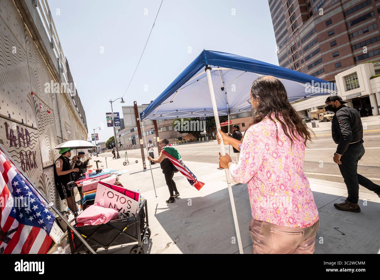 24/7 manifestants anti-GLACE reconstruisent après que le LAPD et les agents sanitaires de la ville ont nettoyé la nourriture, l'eau et les auvents du campement de protestation devant le 300 North Los Angeles Federal Building dans le centre-ville de Los Angeles. La police a cité les codes municipaux relatifs aux campements de sans-abri, suscitant les critiques des activistes et des membres de la communauté. 18 juillet 2025. Banque D'Images