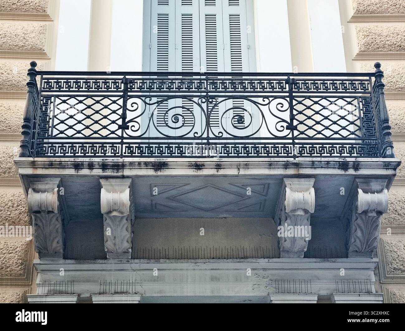 Gracieuse grille en fer forgé avec des formes en spirale et ornement grec traditionnel, décorant un balcon de bâtiment dans le centre historique d'Athènes Banque D'Images