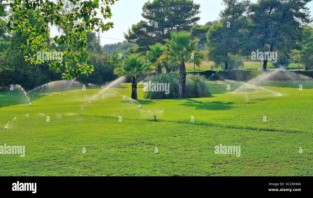 Système d'irrigation automatique pour une pelouse verte sur le territoire d'un hôtel grec par une chaude journée d'été Banque D'Images