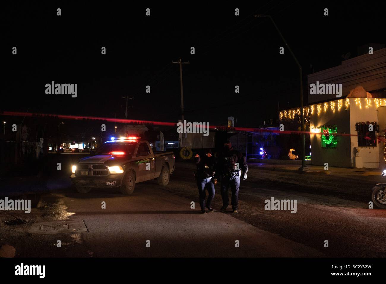 La police sécurise une scène de crime au milieu des lumières de vacances à Ciudad Juarez, reflétant la lutte continue de la ville contre la violence urbaine. Banque D'Images