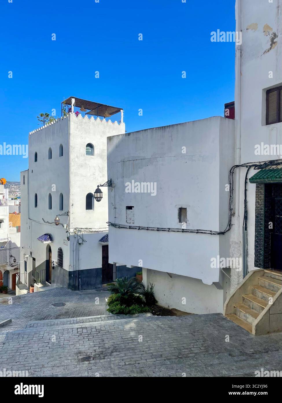 Scène de rue avec des bâtiments blanchis à la chaux, des fenêtres cintrées et un chemin pavé. Vieille Médina, Tanger, Maroc 01 octobre 2025. Banque D'Images