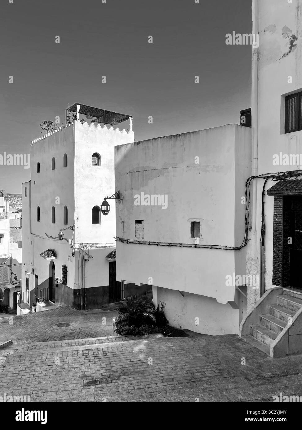 Scène de rue avec des bâtiments blanchis à la chaux, des fenêtres cintrées et un chemin pavé. Vieille Médina, Tanger, Maroc 01 octobre 2025. Banque D'Images