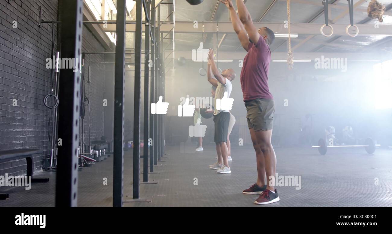 Homme en Bourgogne tenant le medecine ball au-dessus de la salle de gym fonctionnelle, avec gréement, haltères, espace de copie Banque D'Images