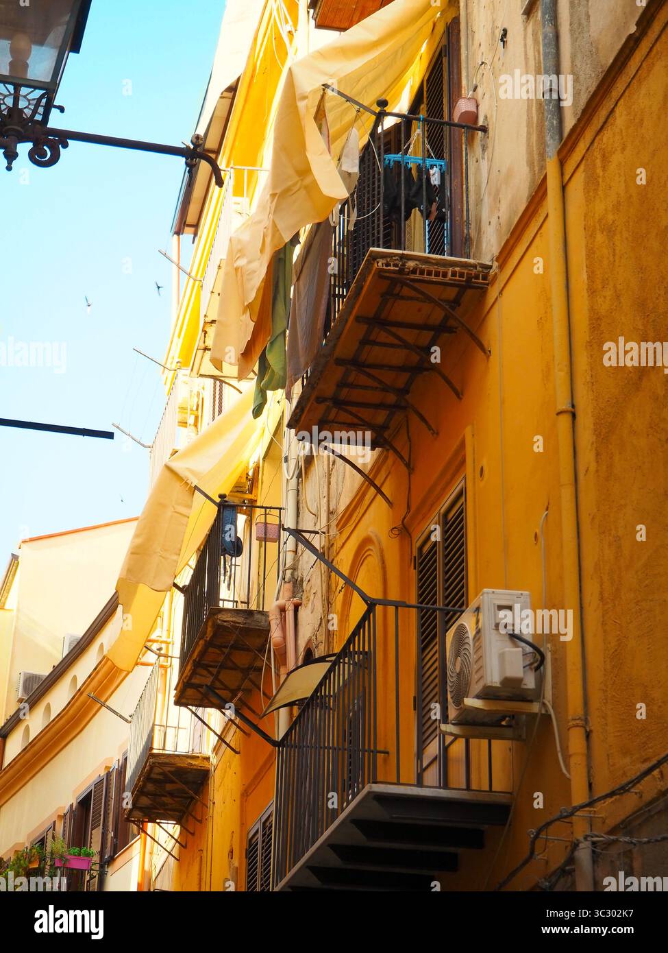 Blanchisserie soufflant dans le vent sur une rue ensoleillée de Palerme avec des façades historiques Banque D'Images