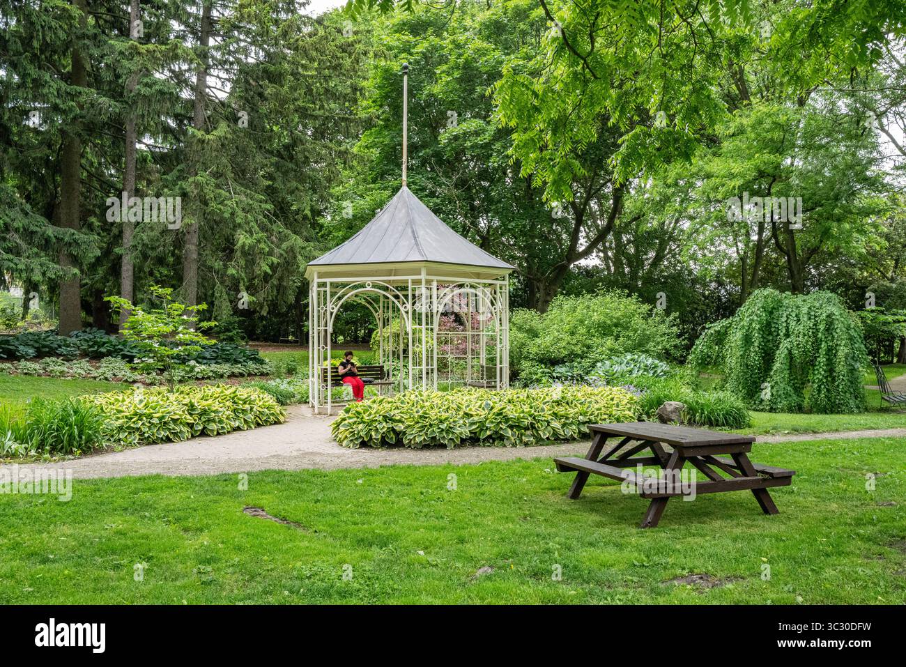 Une femme est assise seule dans un belvédère dans les jardins shakespeariens près de la rivière Avon dans la ville inspirée de Stratford-upon-Avon en Angleterre. Banque D'Images