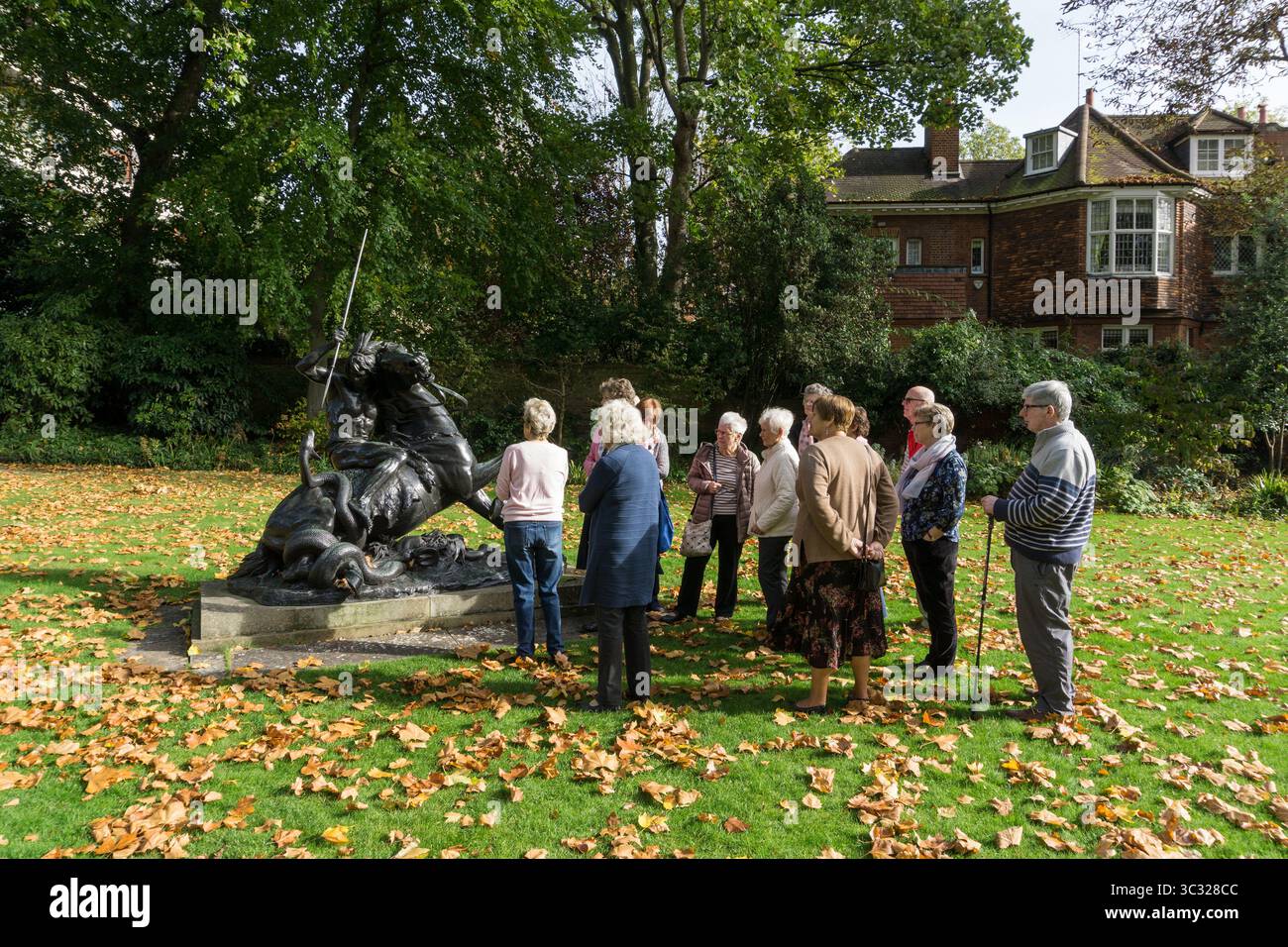 Une fête de tournée, membres de l'U3A, dans le jardin de Leighton House, Londres, Royaume-Uni ; regarder Un moment de péril, une sculpture de Thomas Brock Banque D'Images