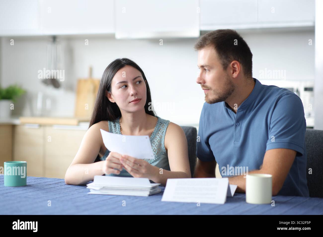 Couple interracial sérieux parlant de relevé bancaire dans la cuisine à la maison Banque D'Images