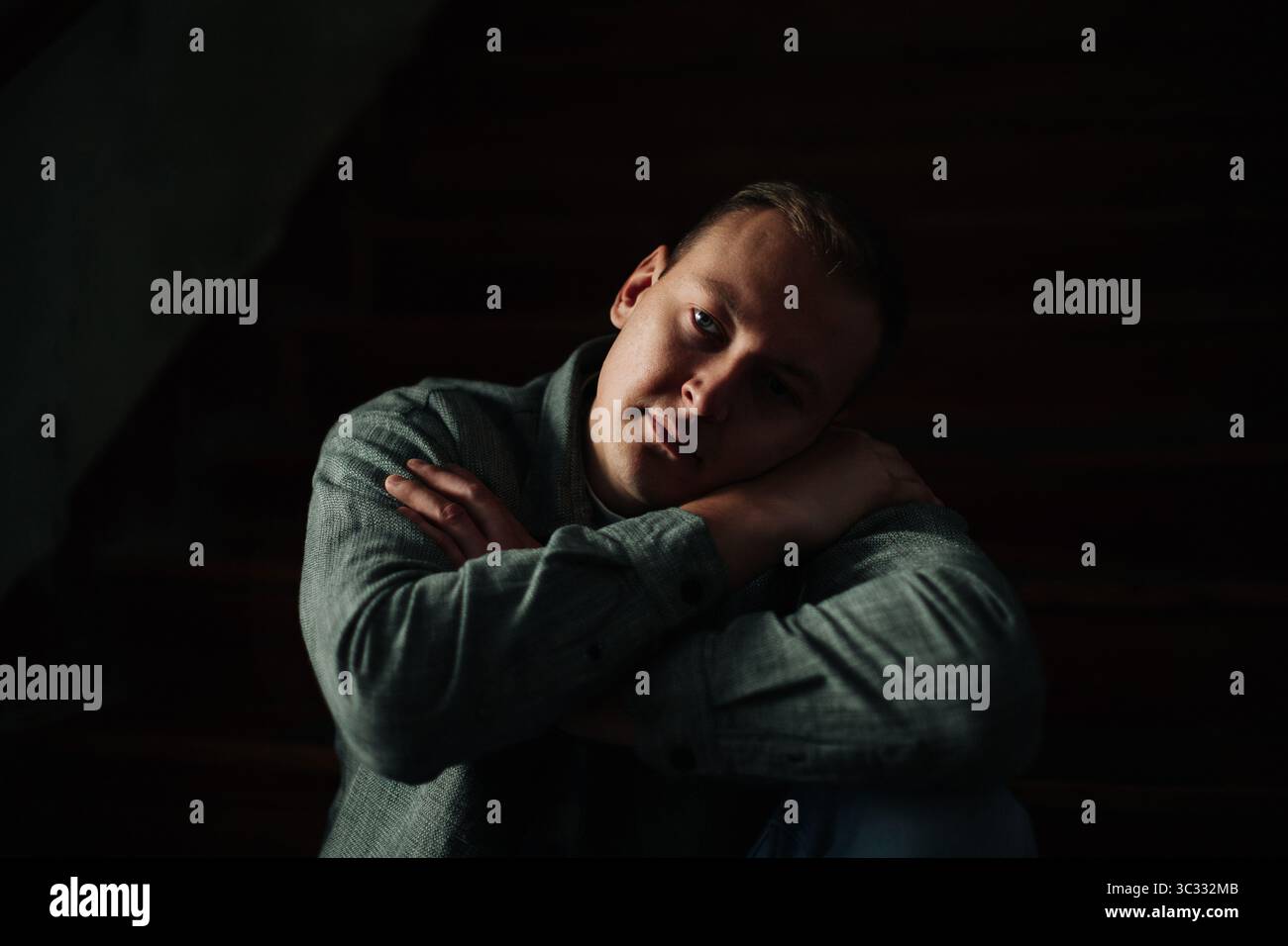 Homme assis dans l'ombre avec une expression réfléchie Banque D'Images
