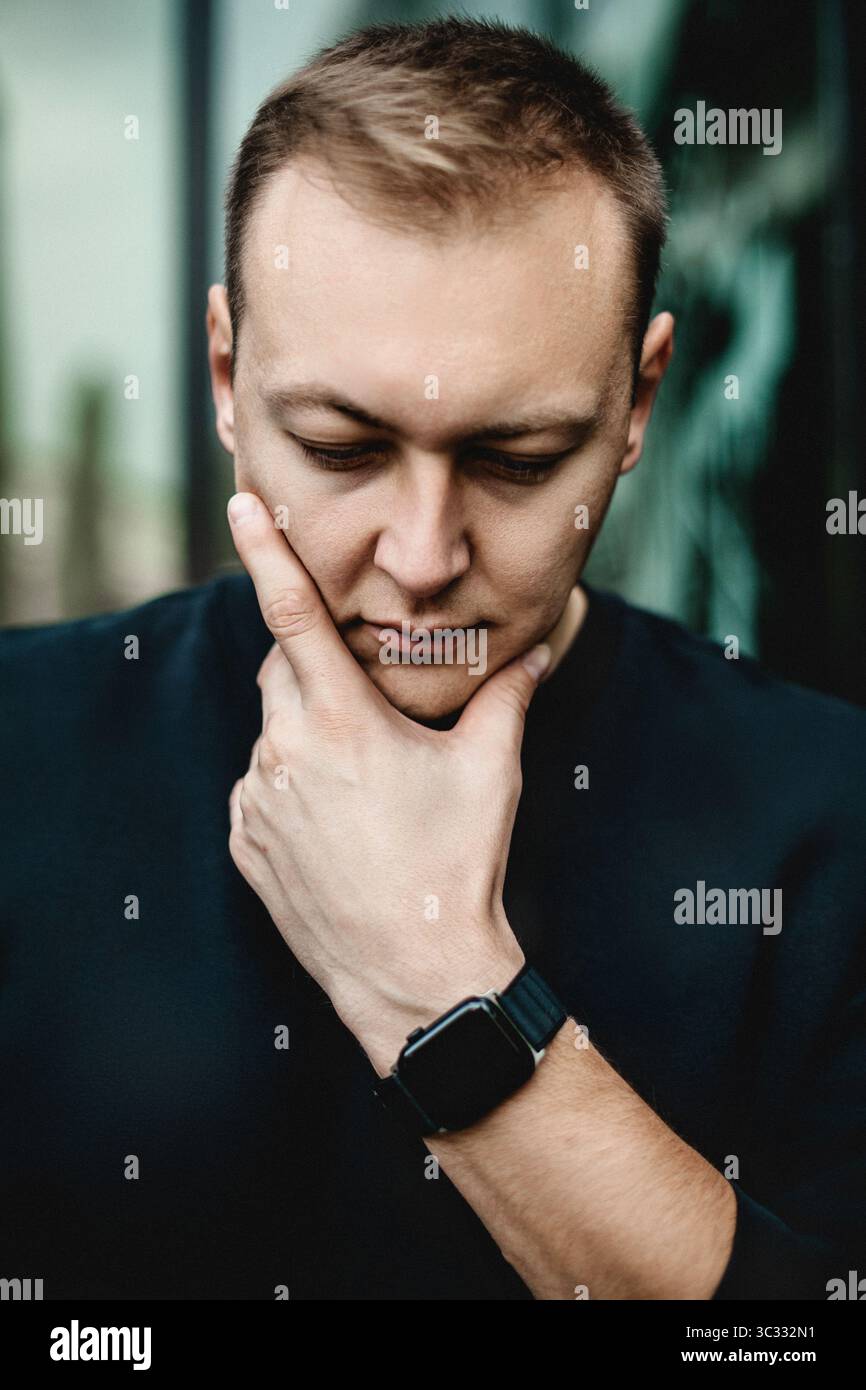 Homme pensant avec la main sur le menton en milieu urbain Banque D'Images
