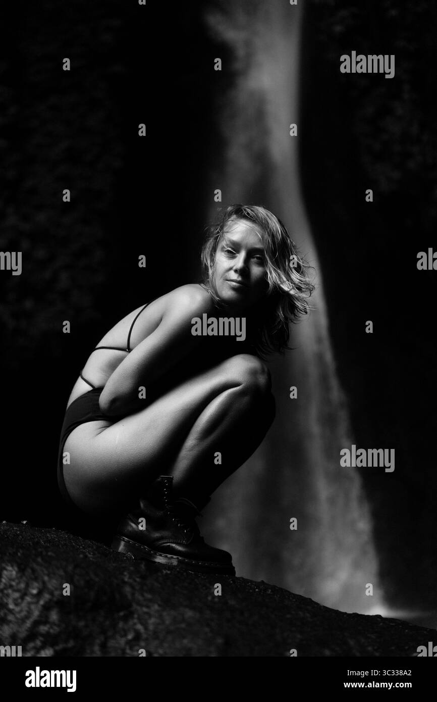 Femme sur la roche couverte de mousse, jungle tropicale luxuriante près de la cascade Banque D'Images