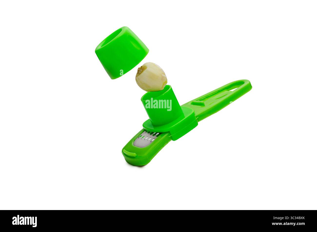Un outil de cuisine en plastique vert presse à ail avec une seule gousse d'ail pelée placée entre ses compartiments, isolé sur un fond blanc. L'image Banque D'Images