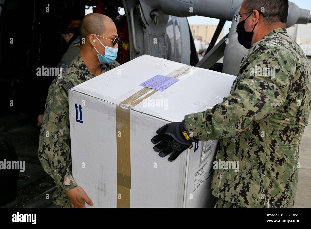 9 mars 2020 - Sigonella, Italie - le spécialiste en chef de la logistique Wilder Fermangomez, à gauche, et le spécialiste de la logistique de 1re classe Rolando sol, tous deux affectés à la Defense Logistics Agency distribution Sigonella, chargent une boîte de vaccins COVID-19 sur un hélicoptère MH-60S Sea Hawk, affecté à l'Helicopter Sea combat Squadron (HSC) 7, pour le transport vers le porte-avions de classe Nimitz USS Dwight D. Eisenhower (CVN 69) depuis la Naval Air Station (NAS) Sigonella, le 10 mars 2021. L'emplacement stratégique de NAS Sigonella permet aux forces américaines, alliées et des Nations partenaires de se déployer et d'intervenir selon les besoins, assurant ainsi la sécurité Banque D'Images