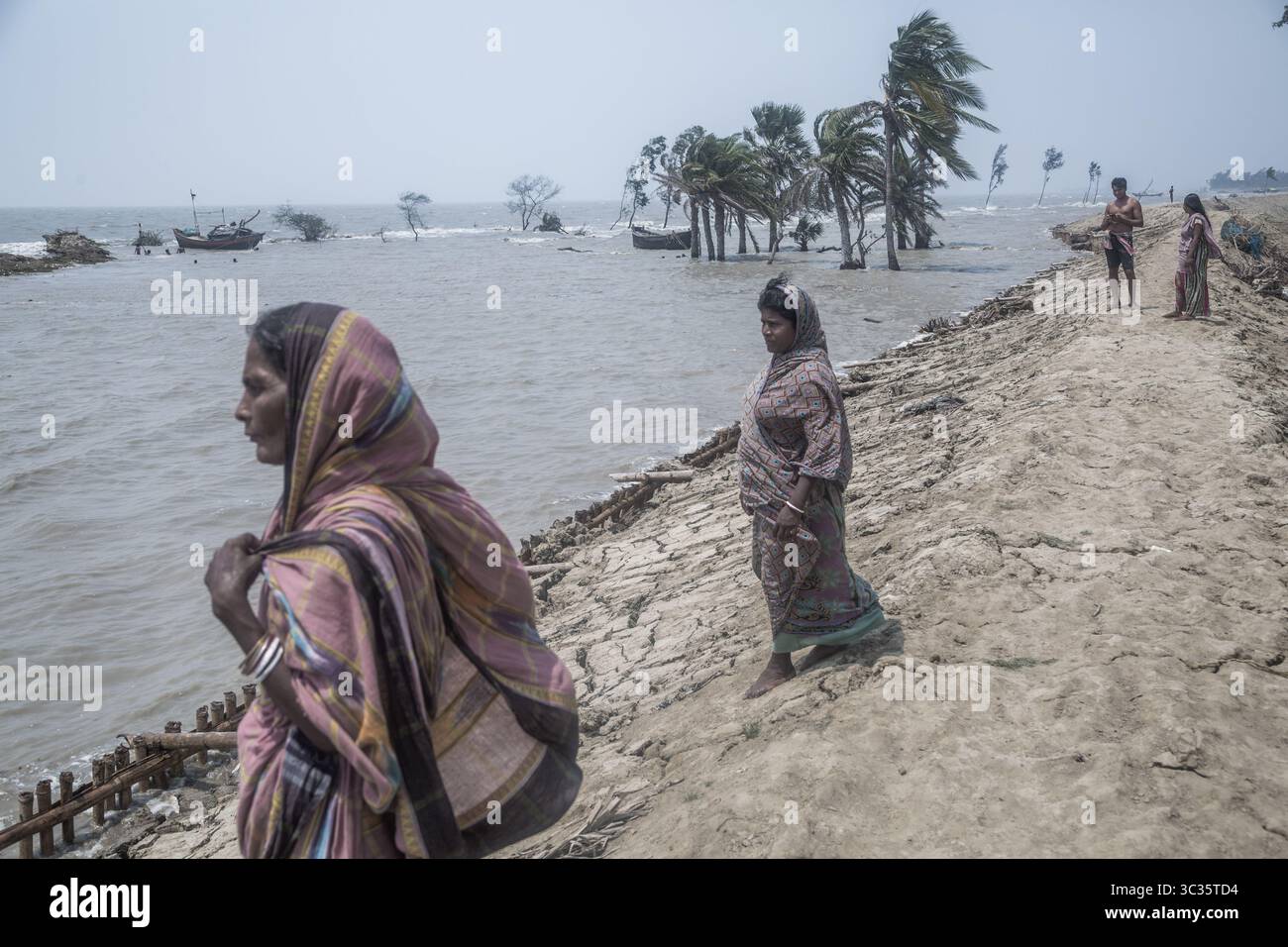 Le 30 mars 2021, Kolkata, Bengale occidental, Inde : les villageois de l'île de Ghoramara se tiennent devant leur village naufragé le jour précédent de la date des élections. Sundarbans, l'un des sites populaires du patrimoine mondial de l'UNESCO, est une préoccupation climatique croissante en raison de l'élévation du niveau de la mer. Sur les 52 îles habitées (sur 102), plusieurs îles sont maintenant au bord de la disparition. Au milieu de l'agitation des élections au Bengale occidental, aucun des partis politiques ne semble parler de l'incertitude climatique. Cependant, les habitants sont d'avis que la mer peut venir à tout moment aujourd'hui ou t Banque D'Images