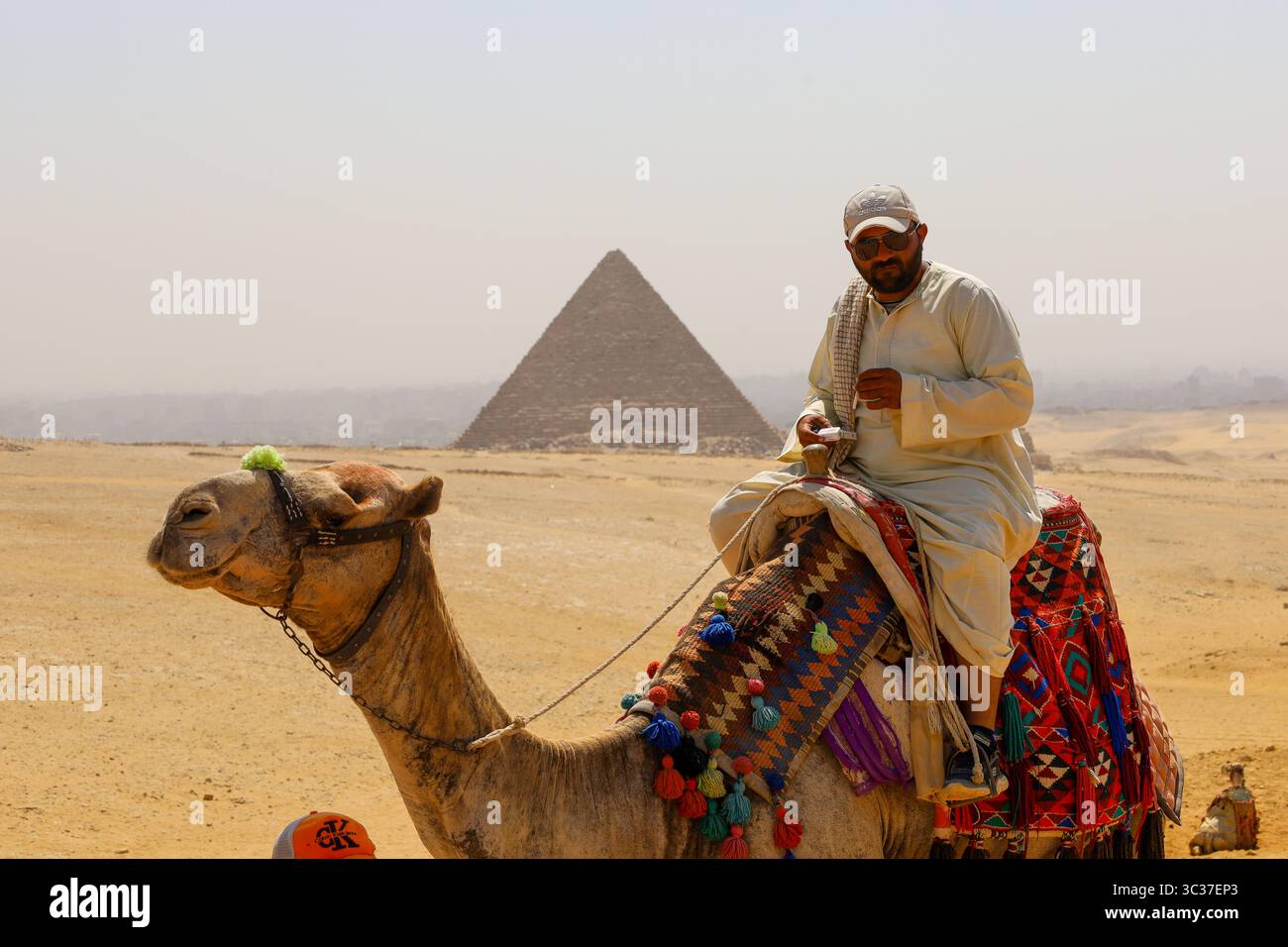 Gizeh, Egypte, 17 juillet 2025 : un touriste chevauchant un chameau devant les pyramides de Gizeh près du Caire Banque D'Images