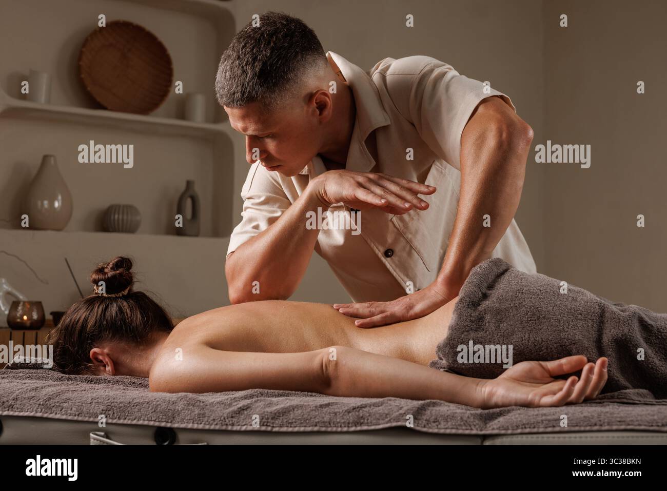 Un thérapeute masculin offre un massage relaxant du dos pour la santé, le soulagement du stress et le bien-être dans un cadre paisible de spa. Banque D'Images