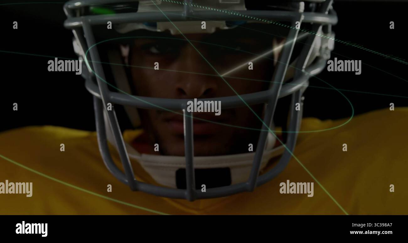 Joueur focalisant portant un casque facial, maillot jaune dans un ensemble sombre, avec des lignes de recouvrement bleues vertes Banque D'Images