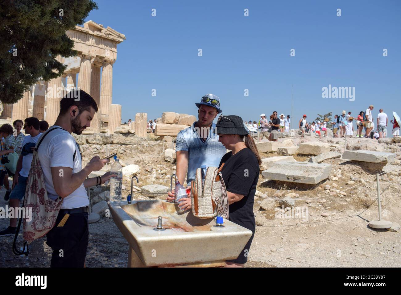 Athènes, Grèce, 24 juillet 2025. Les gens se rafraîchissent avec l'eau du robinet lors de la visite de l'Acropole. Une vague de chaleur sévère frappe la Grèce, poussant les températures à des sommets de plus de 42 degrés Celsius à Athènes et dans d'autres villes. Crédit : Dimitris Aspiotis/Alamy Banque D'Images