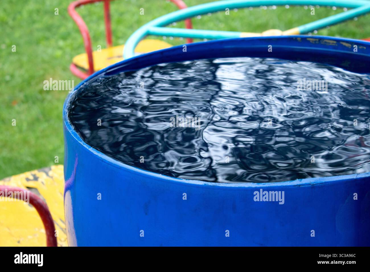 Baril d'eau en plastique bleu réutilisé pour collecter et stocker l'eau de  pluie pour arroser les plantes pleines d'eau et d'eau qui s'égoutte du toit  pendant la somme Photo Stock