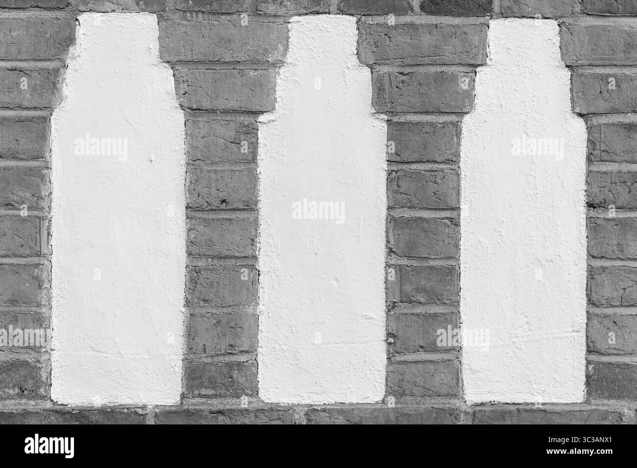 Silhouettes blanches en forme de bouteille peintes sur un mur de briques. Motif répétitif et contraste texturé entre peinture et maçonnerie. Banque D'Images
