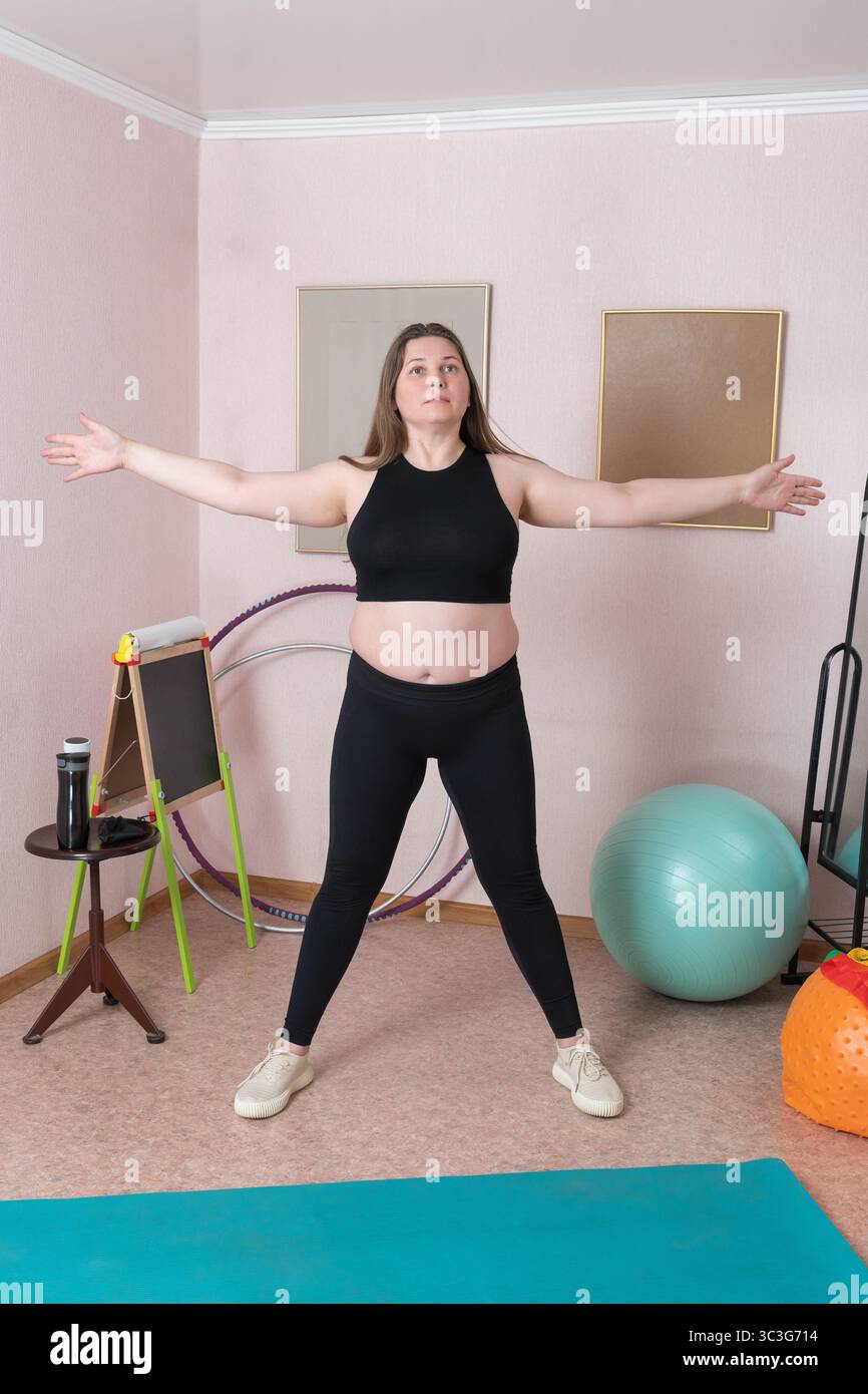 Toute la longueur d'une femme de fitness exécute la pose de cinq étoiles pointues pendant l'entraînement de fitness du matin à la maison. La femme est caucasienne, et est vêtue en spo Banque D'Images