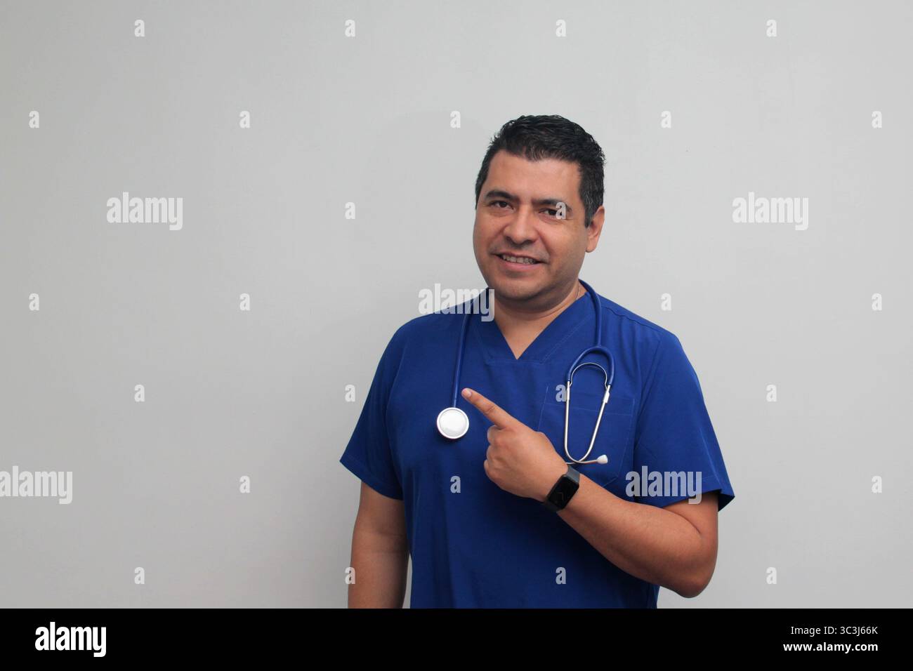 Médecin spécialiste latino-américain à la peau foncée avec un stéthoscope pointe avec son doigt avec une expression de joie et de surprise Banque D'Images Médecin spécialiste latino-américain à la peau foncée avec un stéthoscope pointe avec son doigt avec une expression de joie et de surprise Banque D'Images