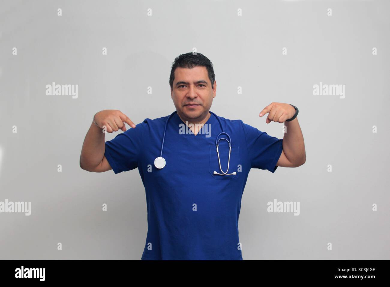 Médecin spécialiste latino-américain à la peau foncée avec un stéthoscope pointe avec son doigt avec une expression de joie et de surprise Banque D'Images Médecin spécialiste latino-américain à la peau foncée avec un stéthoscope pointe avec son doigt avec une expression de joie et de surprise Banque D'Images