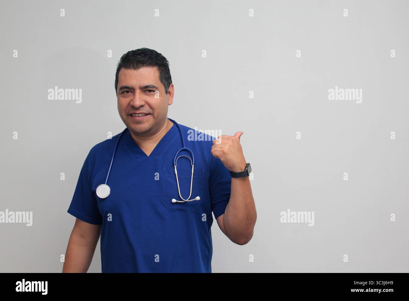 Médecin spécialiste latino-américain à la peau foncée avec un stéthoscope pointe avec son doigt avec une expression de joie et de surprise Banque D'Images Médecin spécialiste latino-américain à la peau foncée avec un stéthoscope pointe avec son doigt avec une expression de joie et de surprise Banque D'Images