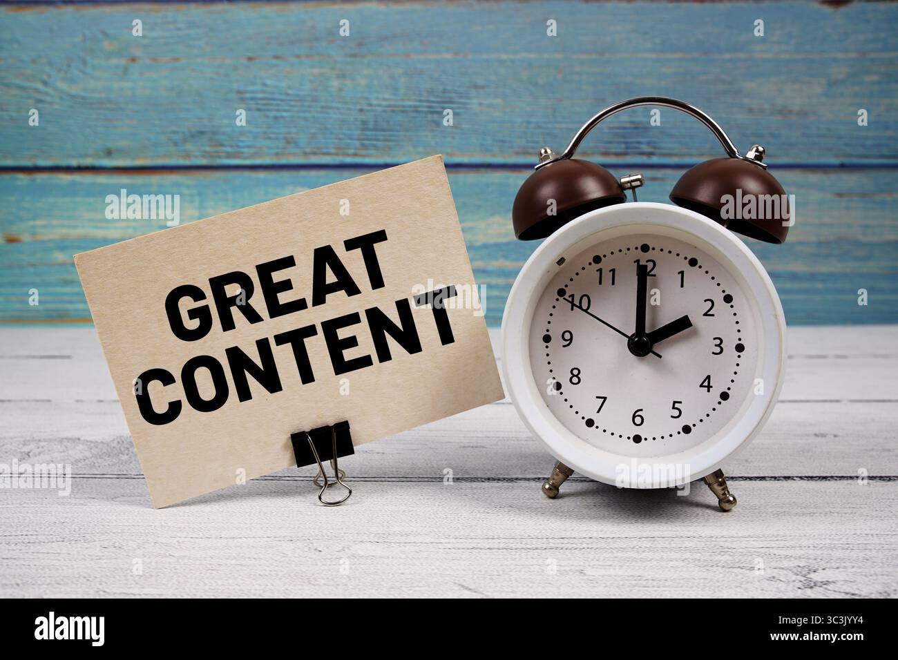 Grand contenu texte écrit sur carte papier avec réveil sur fond en bois Banque D'Images