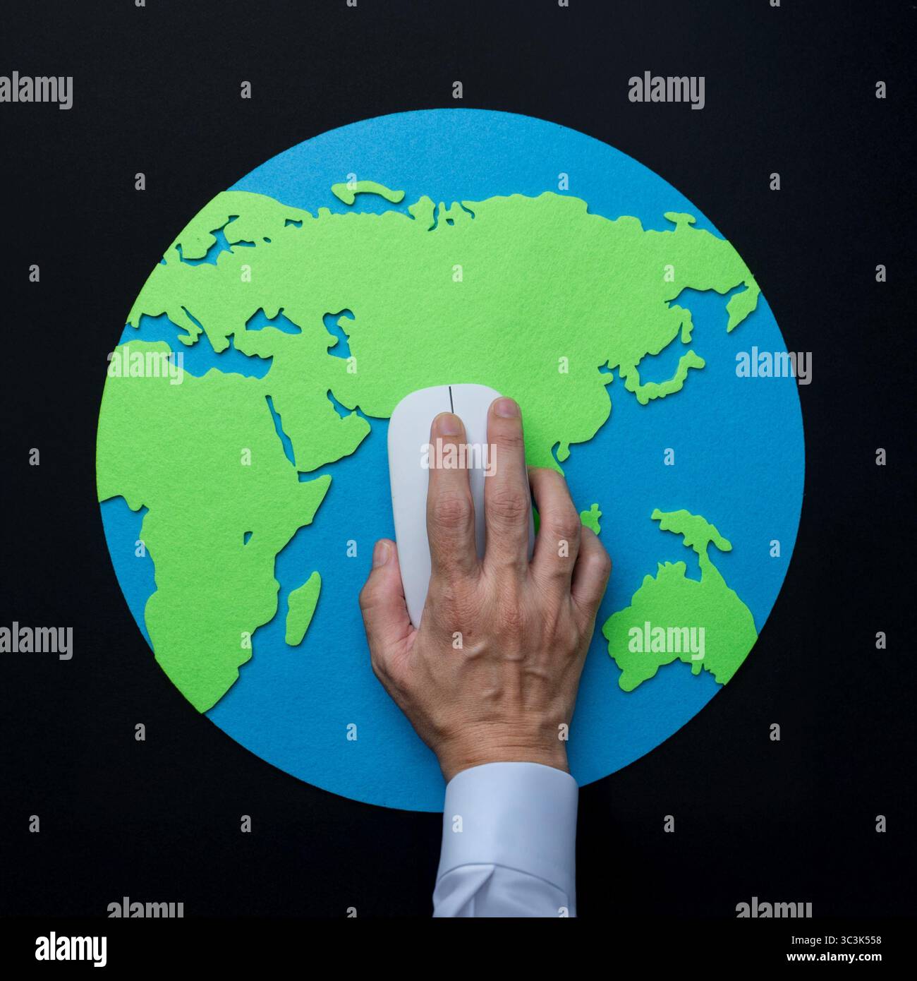 Une photo au-dessus du ciel d'une main actionnant une souris d'ordinateur sur une carte de la Terre. Connectivité mondiale, interaction numérique, concept technologique. Banque D'Images