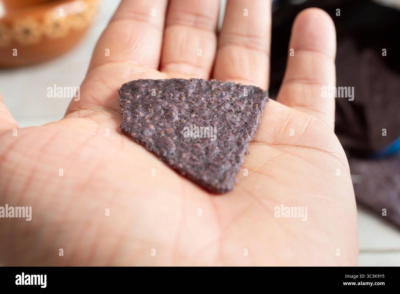 Une vue d'une puce de tortilla de maïs bleue dans la paume de la main. Banque D'Images